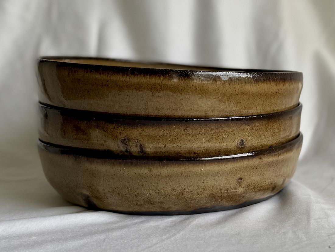 Stack of three olive-brown pasta bowls